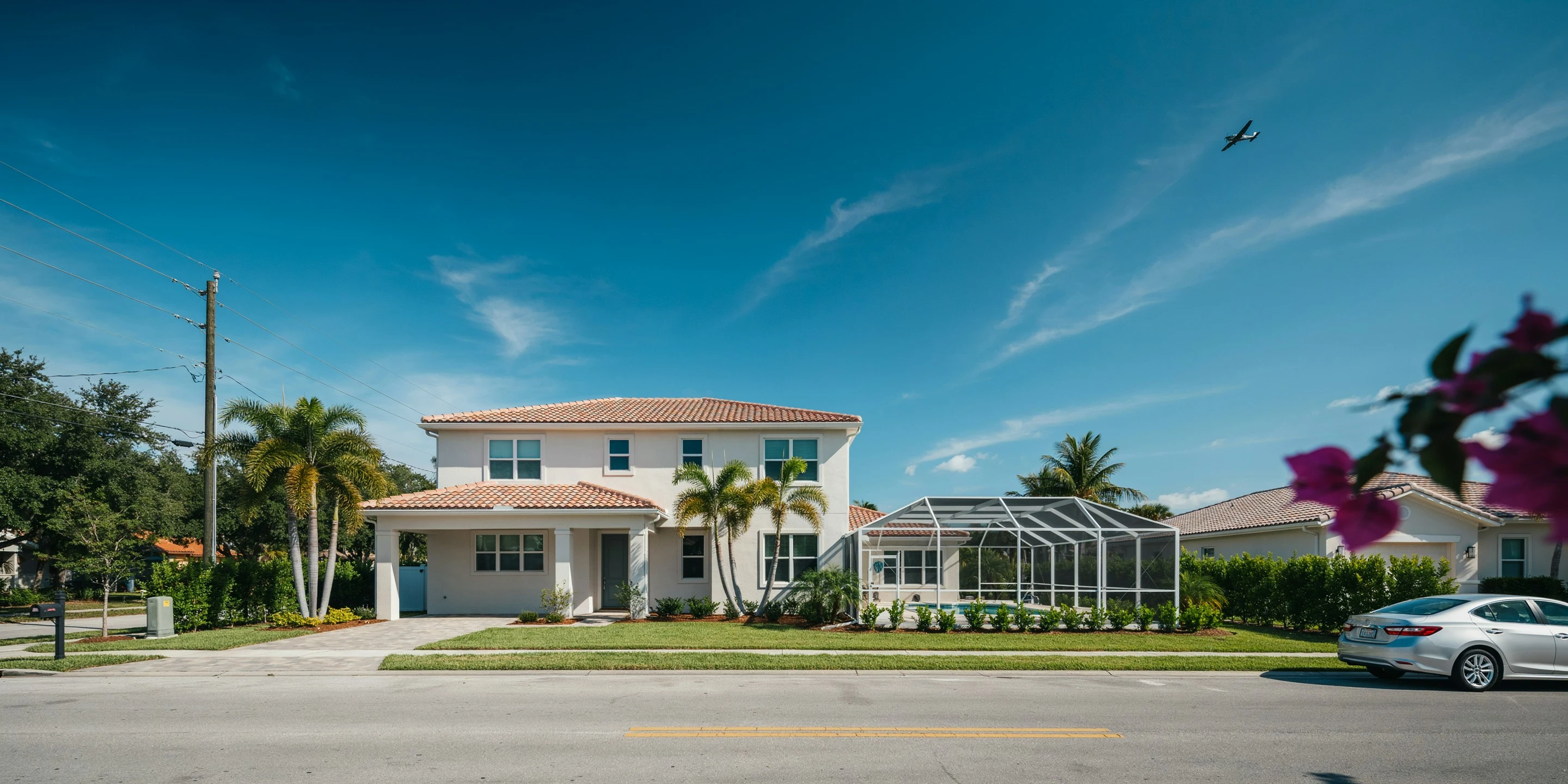 Home with pool cage and a small plane passing overhead on the airport west side, Sarasota, FL