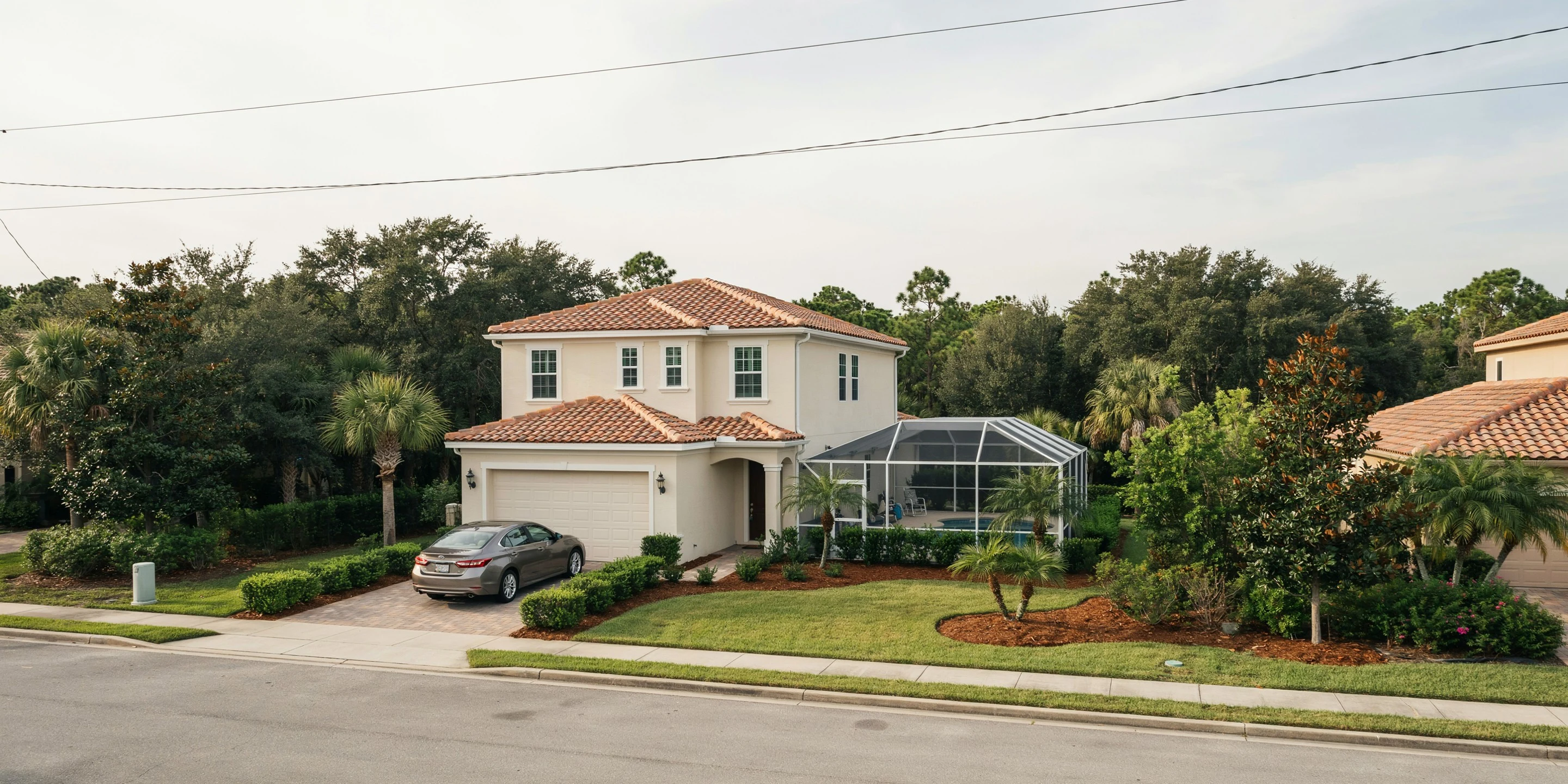 Gated-community home with tile roof and pool cage beside a preserve in University Park, FL